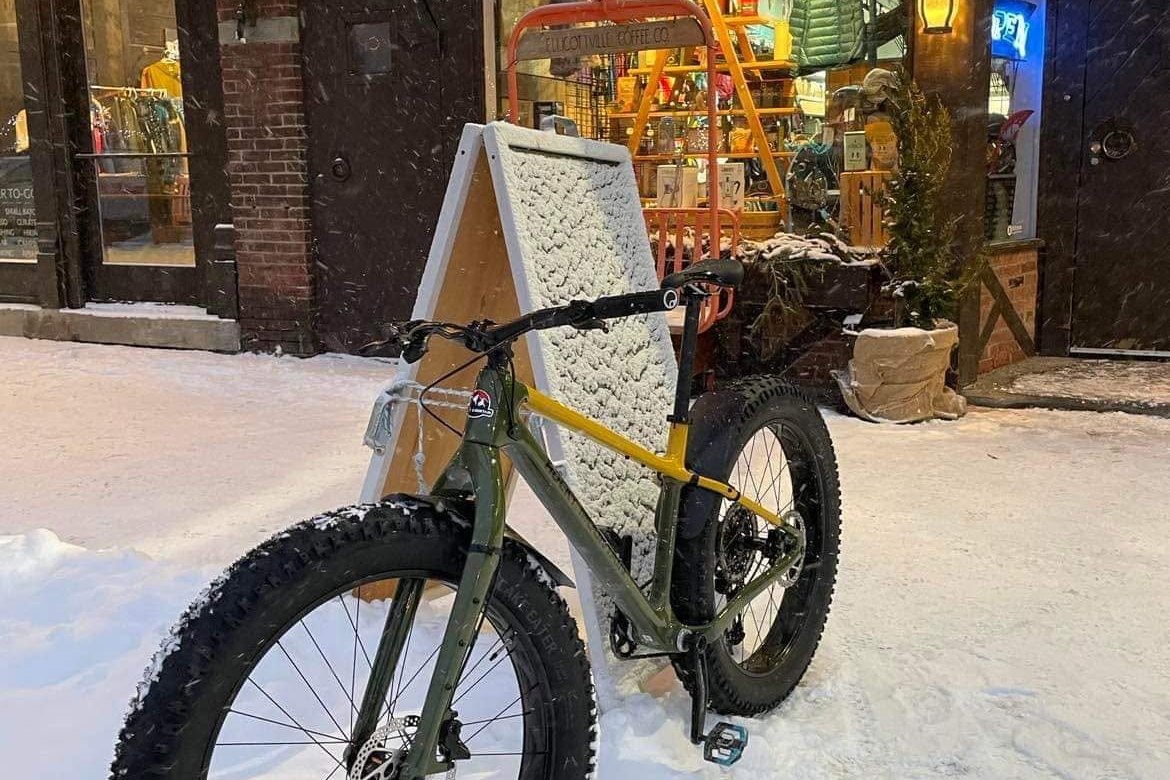 Fat tire bike parked in fresh snow outside Ellicottville Coffee Co in the village at night