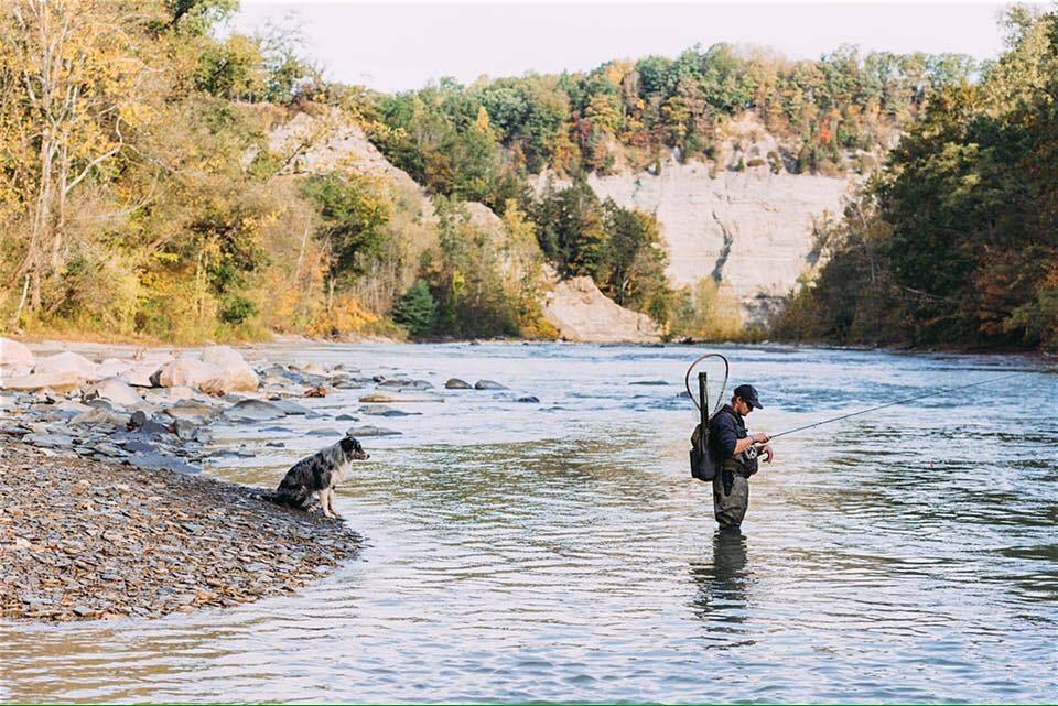Fly fisherman with his dog on a river near Ellicottville