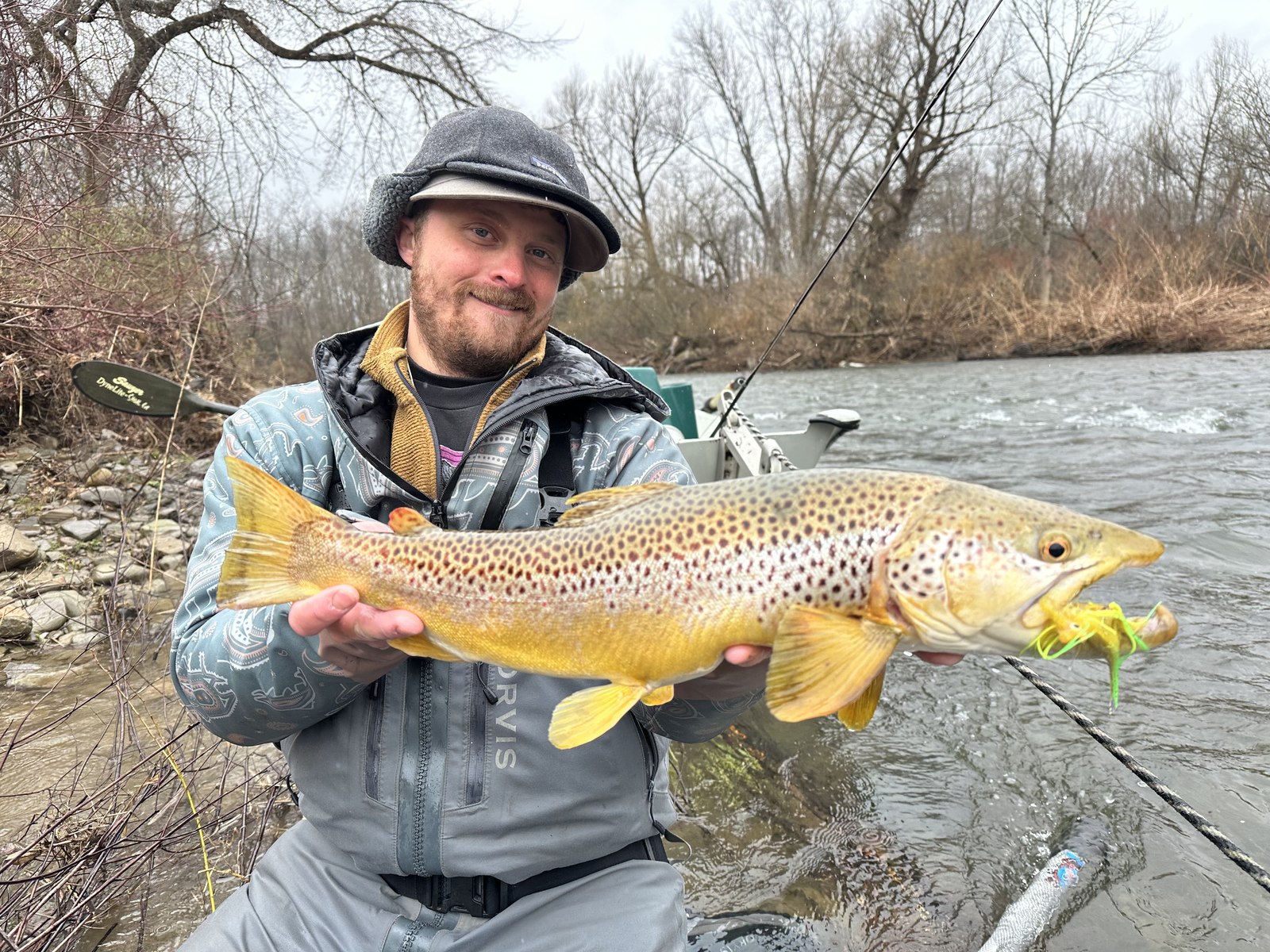 Nick Sagnibene of 716 Fly Fishing holding a large brown trout beside a Western New York river