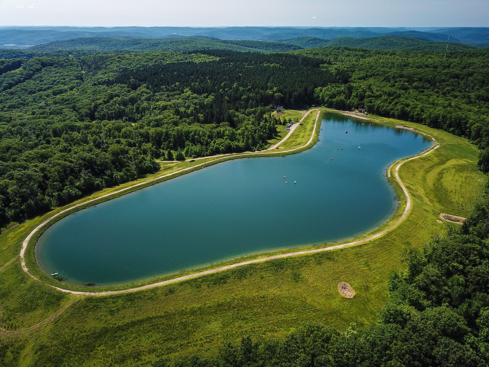 Aerial view of the summit reservoir at Holiday Valley ringed by green hills near Ellicottville