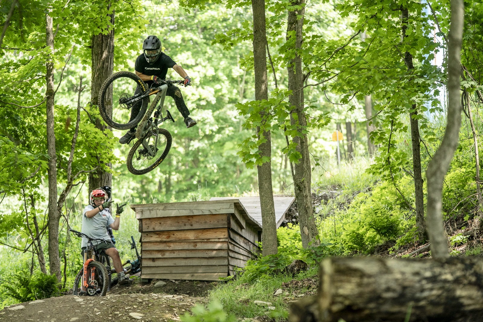 Mountain biker airing a wooden jump feature in the woods at the HoliMont Bike Park