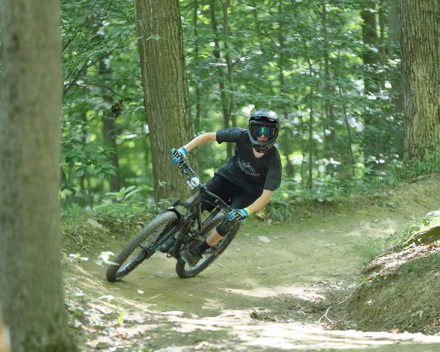 Mountain biker carving a bermed forest trail in Ellicottville in summer
