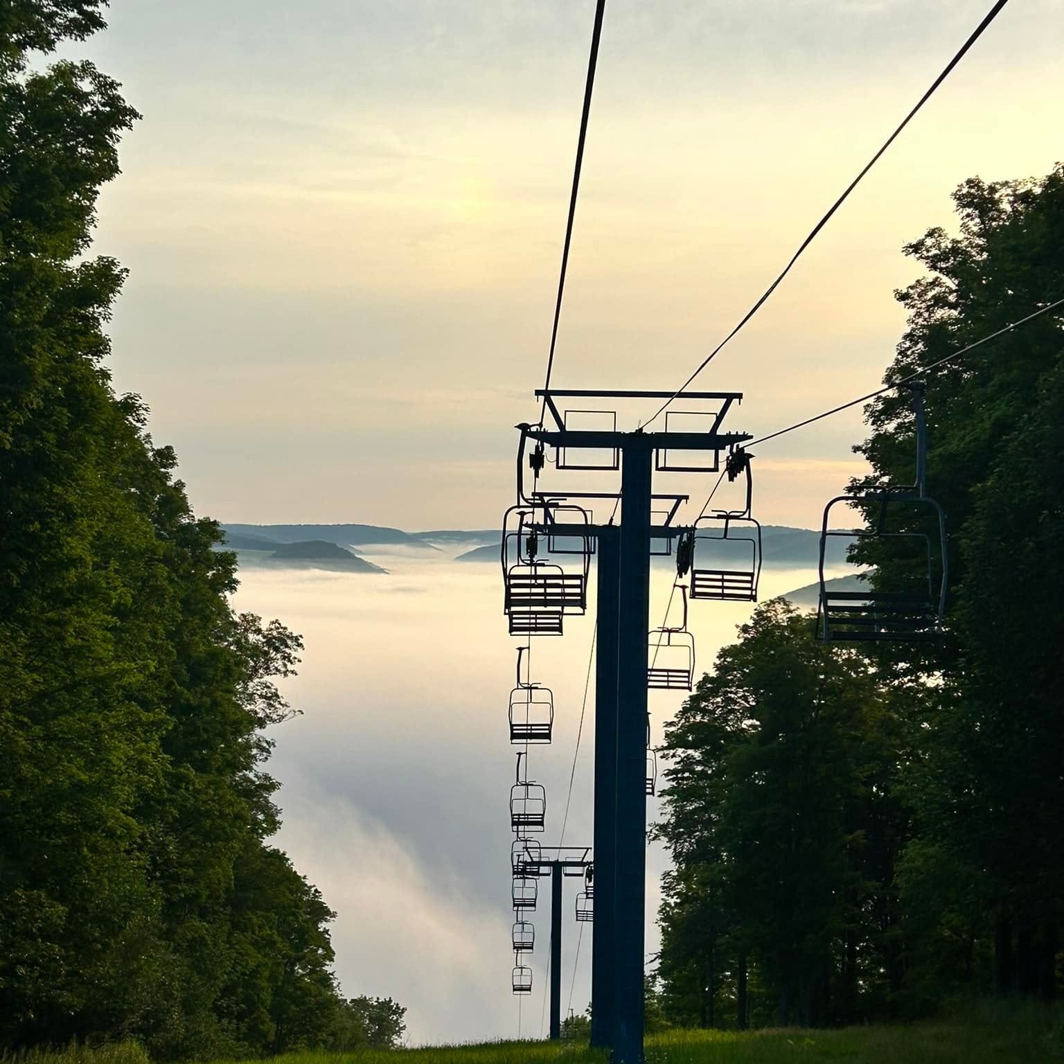Chairlift silhouette above a valley of clouds at dawn in Ellicottville